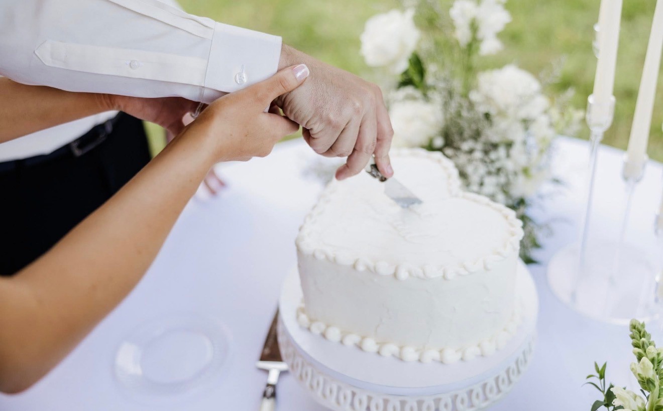 The couple cutting a small white heart-shaped wedding cake