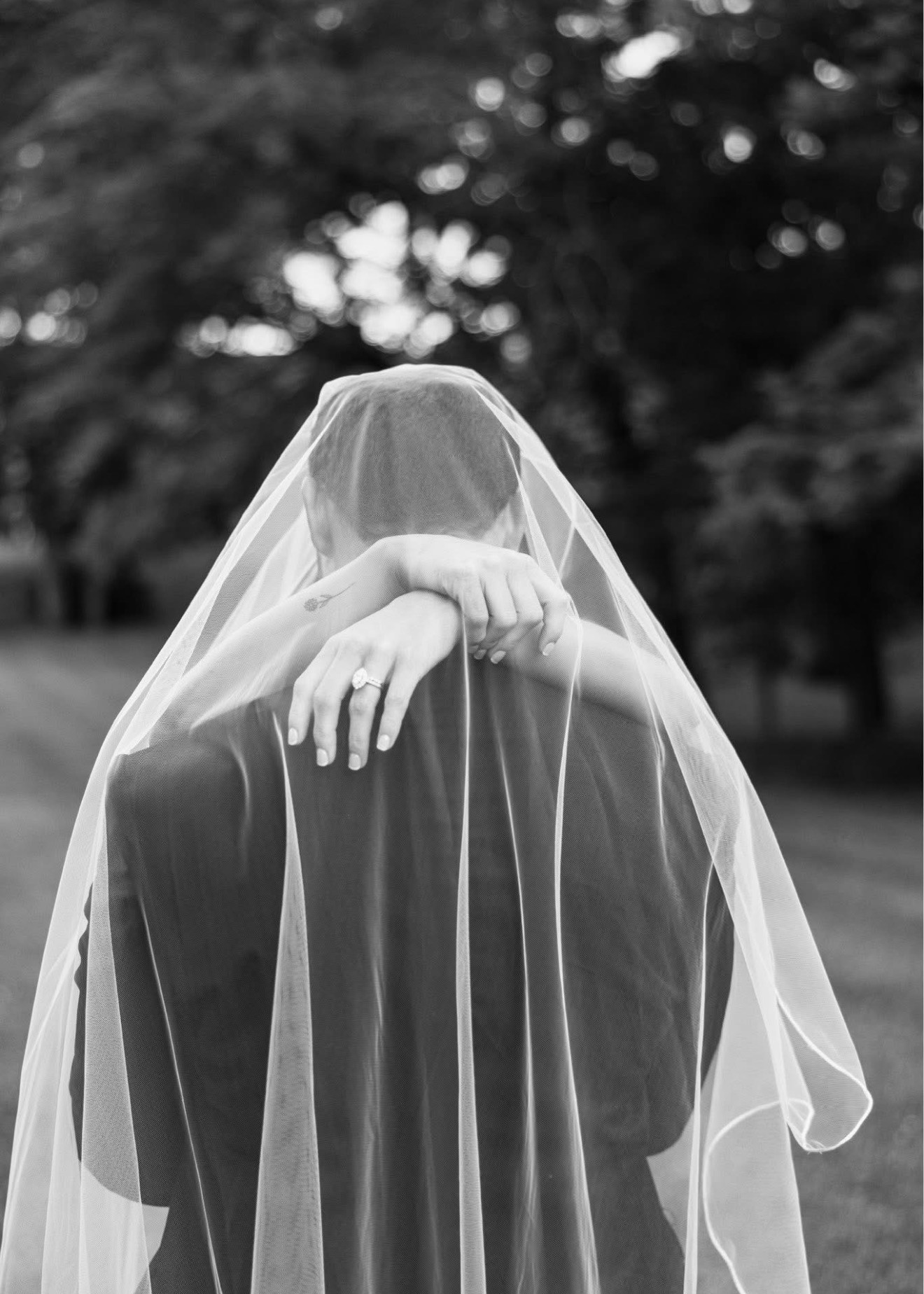 Black and white photo of the bride's arms around the groom's neck under her veil