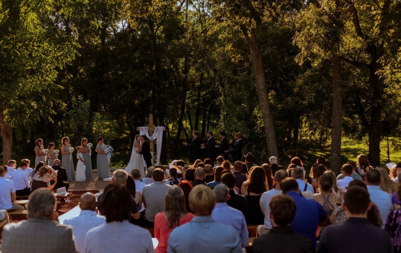 Guests seated in rows facing the outdoor ceremony under tall trees