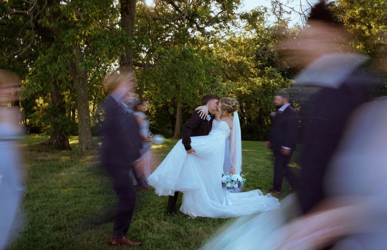 The groom dips the bride for a kiss while guests blur past