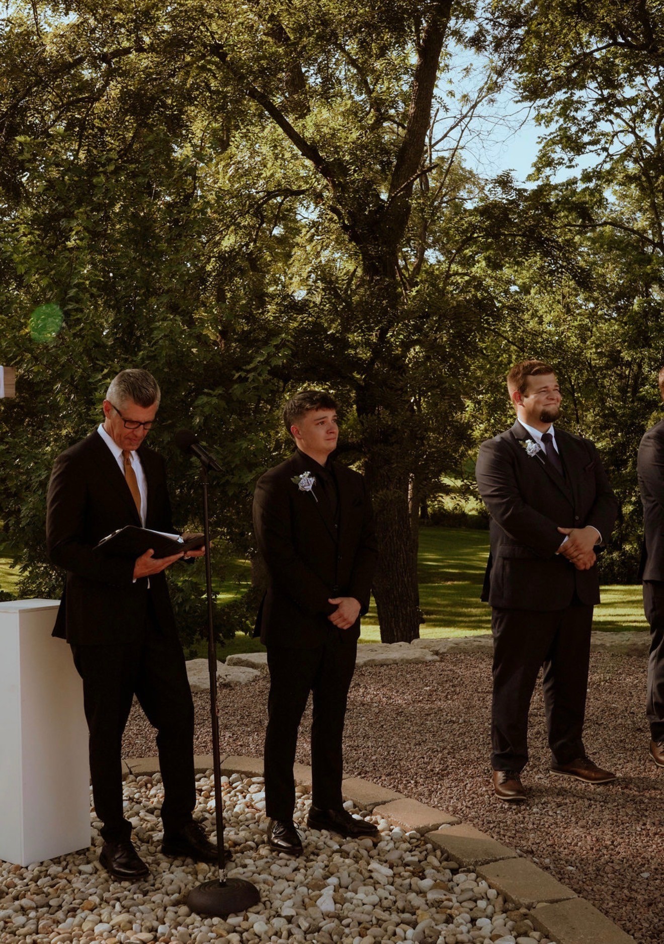 The officiant and groomsmen waiting at the altar on a gravel aisle