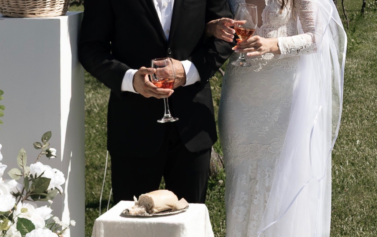 Close detail of the bride and groom holding glasses at a small ceremony table